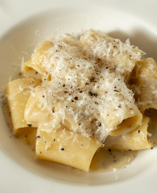 Handmade pasta cacio e pepe topped with grated pecorino