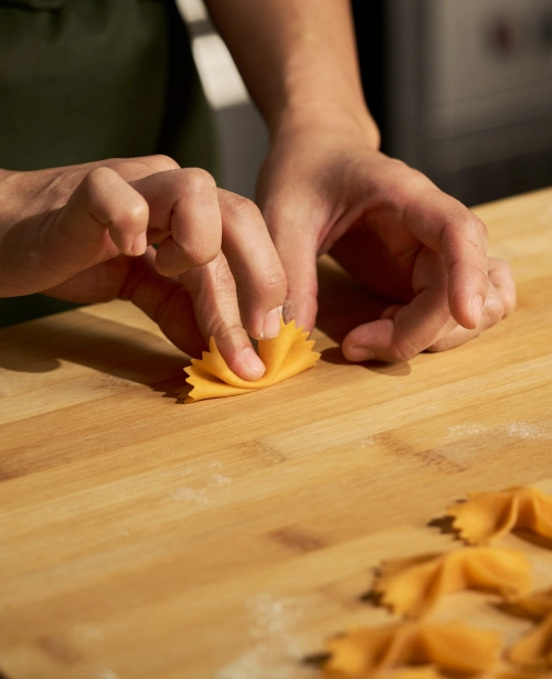 Hands shaping fresh farfalle pasta by hand